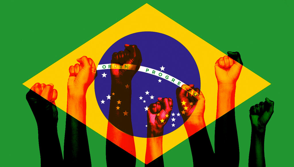 Punhos cerrados em frente à bandeira do Brasil