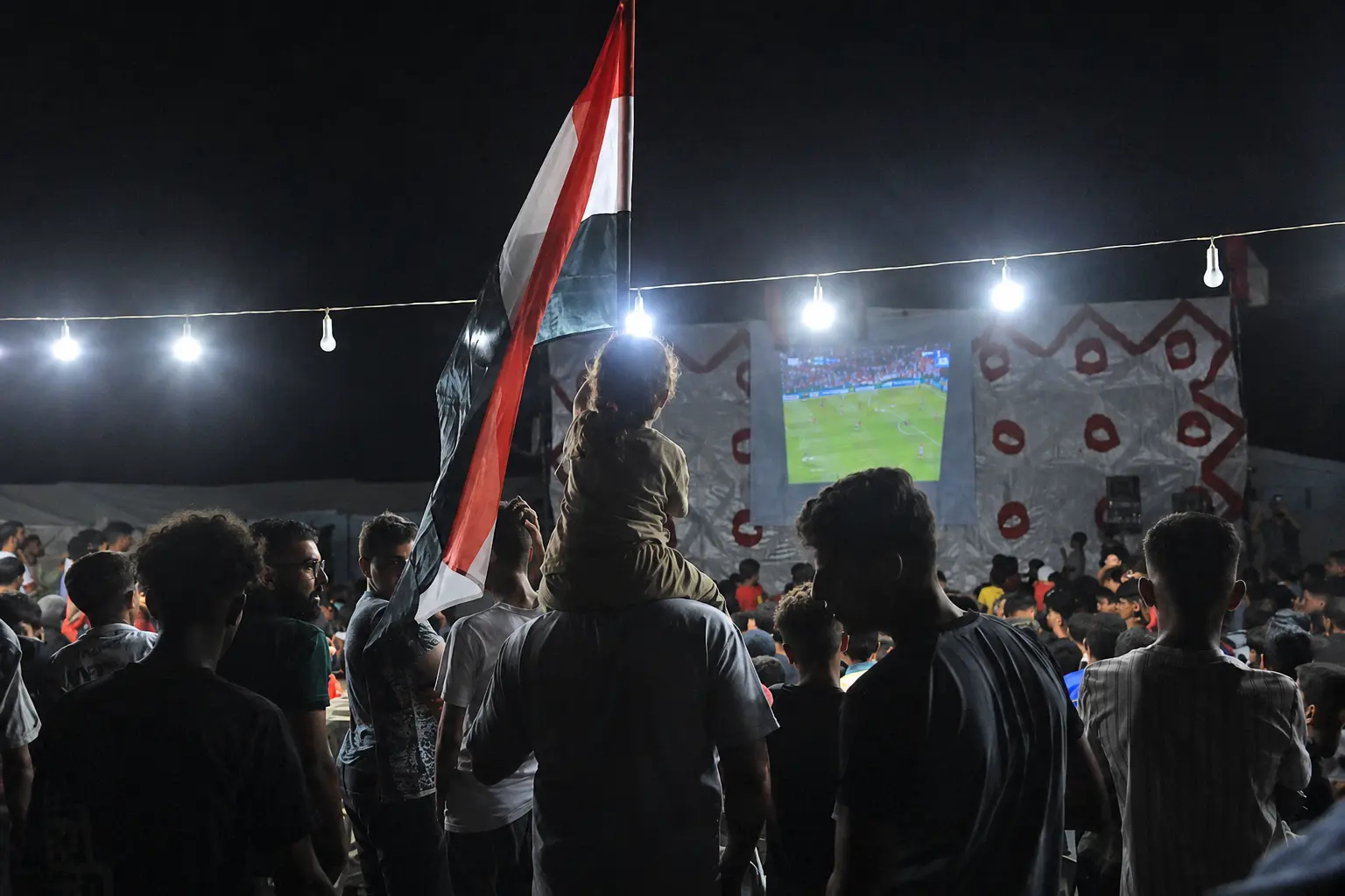 Palestinos assistem à partida entre Bélgica e Egito em Gaza. 15/06/2026. (Foto: Mazen Breem / Mondoweiss)