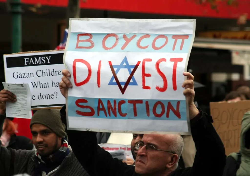 Homem carrega cartaz pedindo boicote, desinvestimento e sanções a Israel durante protesto em Melbourne, na Austrália. (Foto: Takver / Flickr)