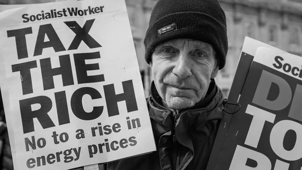 Homem segura cartaz dizendo "taxem os ricos" durante manifestação em Westminster, na Inglaterra. (Foto: Alisdare Hickson / Flickr)